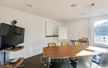 Bright office space rental at Bahnhofstrasse 100, Zürich Center with conference table, chairs, TV, and whiteboard.